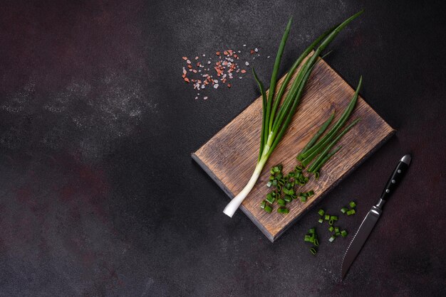 Fresh green onions on a cutting board Dark concrete background