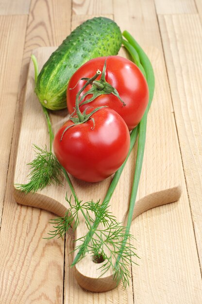 커팅 보드에 신선한 녹색 양파, 딜, 토마토, 오이