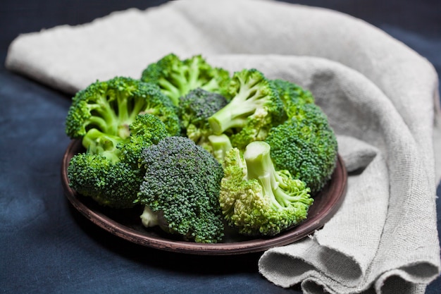 Fresh green organic broccoli in brown plate and linen napkin.