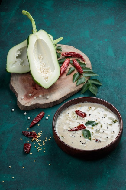 Fresh green papaya splits  and arranged on a wooden piece with  a wooden bowl full of raitha