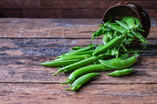 Fresh green pea in bowl on wooden background