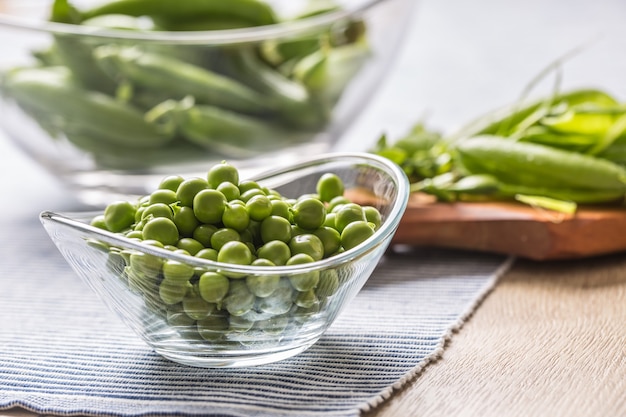 Fresh green pea seeds in bowl on kitchen table.