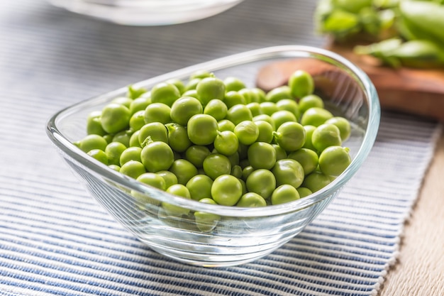 Fresh green pea seeds in bowl on kitchen table.