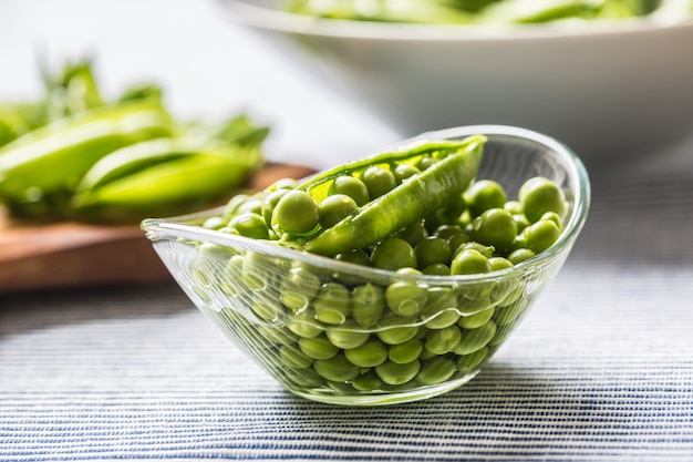 Fresh green pea seeds in bowl on kitchen table.