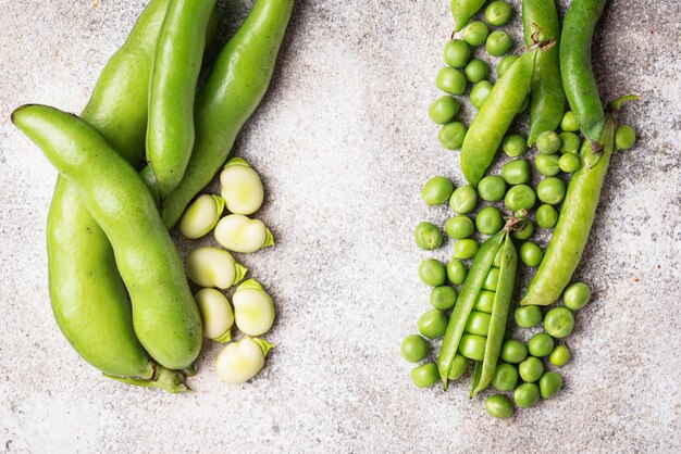 Fresh green peas and beans on light background