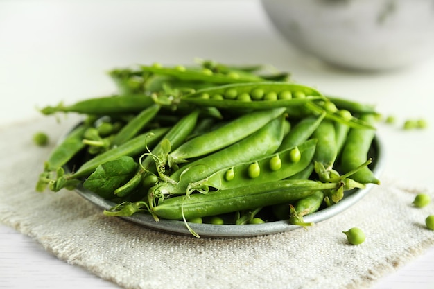 Fresh green peas in plate on napkin