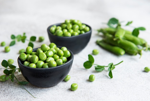 Fresh green peas pods and green peas with sprouts on concrete background. Concept of healthy eating, fresh vegetables.