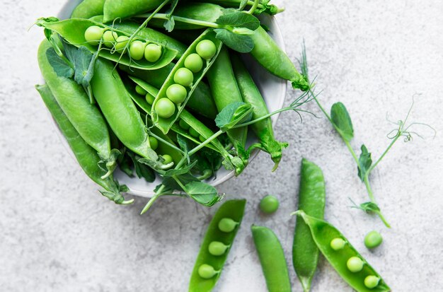 Fresh green peas pods and green peas with sprouts on concrete background