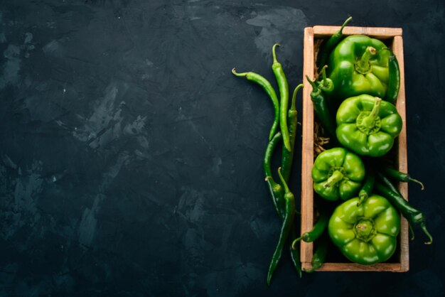 Peperone verde fresco e peperoncino in una scatola di legno vista dall'alto spazio libero per il testo