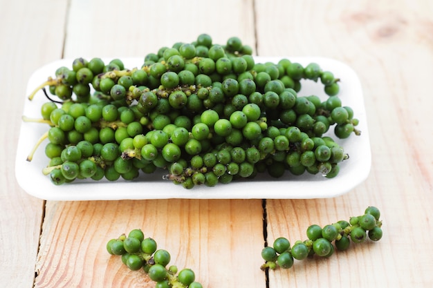 Fresh green Pepper nigrum on white plate.