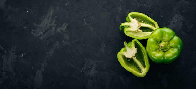 Fresh green pepper in a wooden box On a black stone background Top view Free space for text