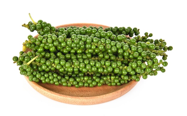 Fresh green peppercorns in wooden dish isolated on a white background