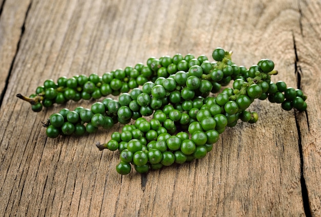 Fresh green peppercorns on wooden table