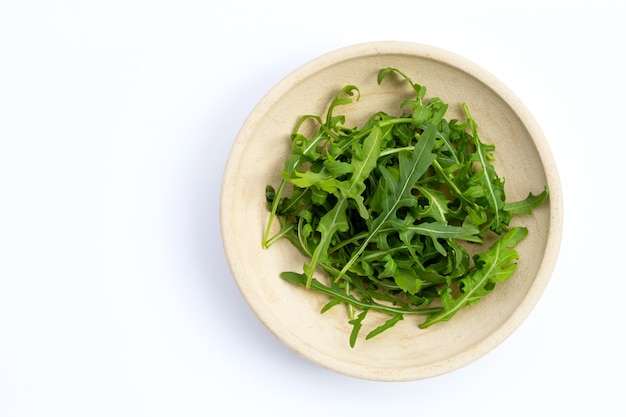 Insalata di rucola verde fresca su priorità bassa bianca.