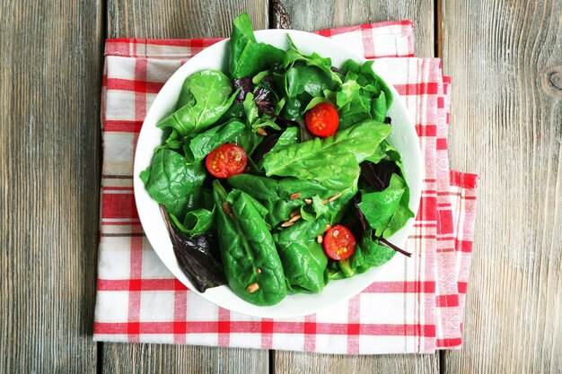 Fresh green salad in bowl on wooden table