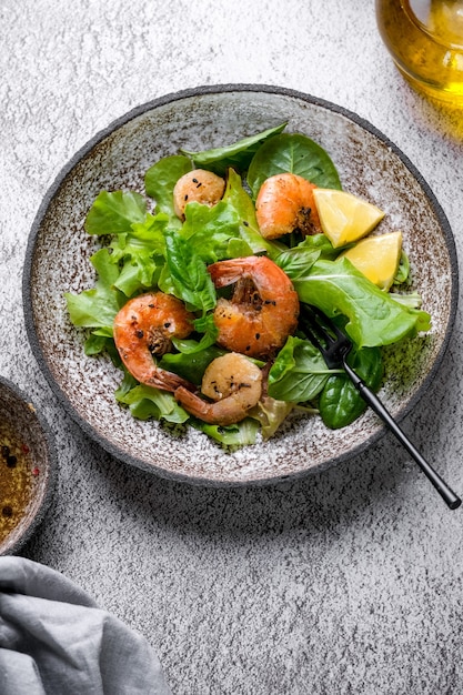 Fresh green salad with basil leaves fried shrimps and lemon Close up dish with copy space