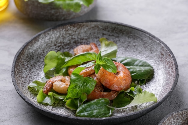 Fresh green salad with basil leaves fried shrimps and lemon Close up dish with copy space