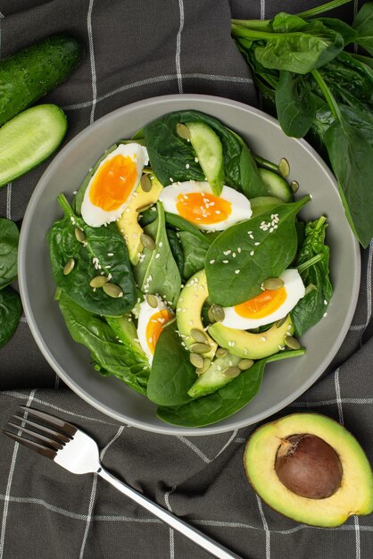 Fresh green salad with egg avocado and spinach on a gray background in a gray plate