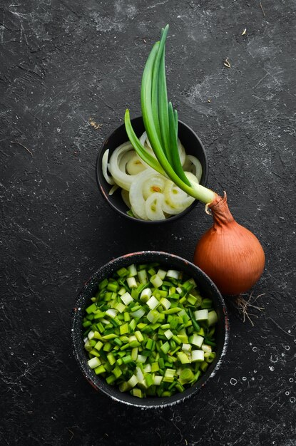 Foto cipolla affettata verde fresca in una ciotola. su uno sfondo nero.