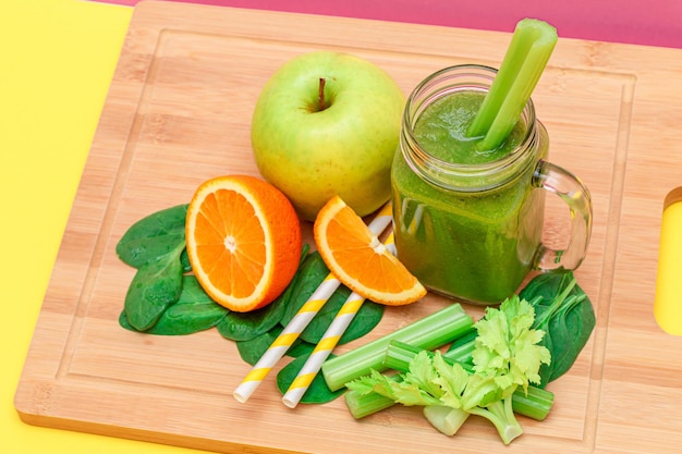 Fresh green smoothie of apple celery spinach and orange in glass smoothie jar