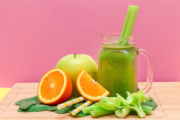 Fresh Green Smoothie of Apple Celery Spinach and Orange in Glass Smoothie Jar