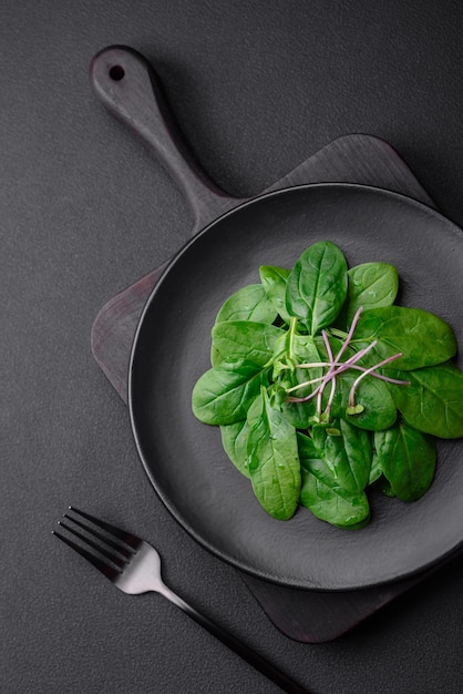 Photo fresh green spinach leaves on a black ceramic plate