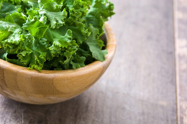 Fresh green superfood kale in wooden bowl leaves on wooden background.Copyspace