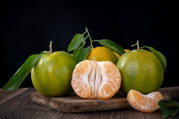 Fresh green tangerine mandarin orange on dark wooden table background