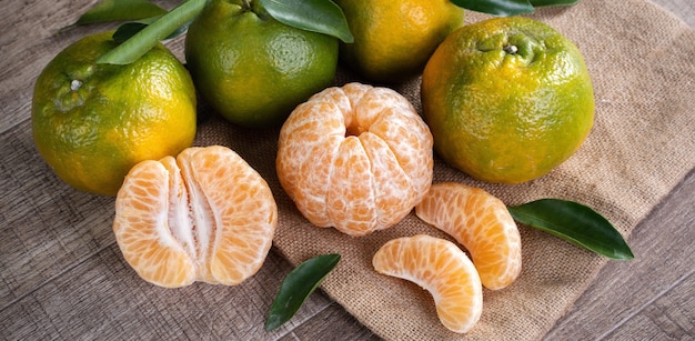 Photo fresh green tangerine mandarin orange with fresh leaves on dark wooden table background harvest concept.