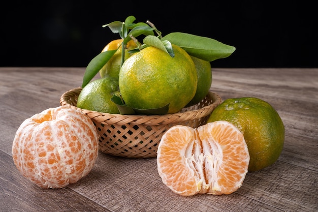 Photo fresh green tangerine mandarin orange with fresh leaves on dark wooden table background harvest concept.