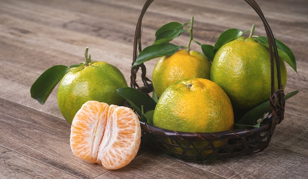 Fresh green tangerine mandarin orange with fresh leaves on dark wooden table background harvest concept.