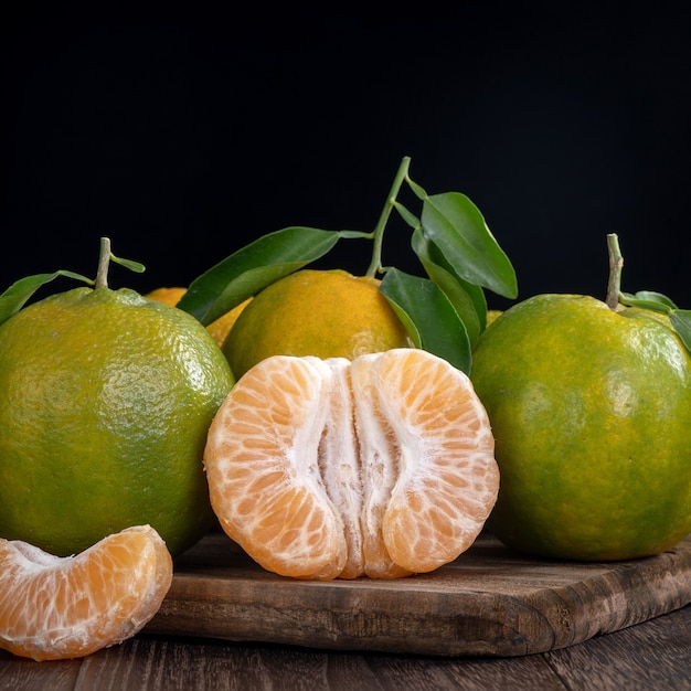 Foto mandarino verde fresco del mandarino con le foglie fresche sul concetto del raccolto del fondo della tavola di legno scuro.