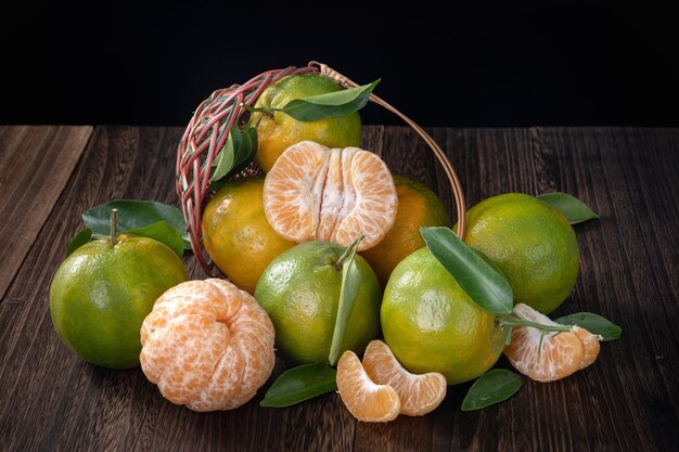 Fresh green tangerine mandarin orange with fresh leaves on dark wooden table background harvest concept.