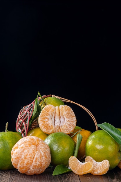 Foto mandarino verde fresco del mandarino con le foglie fresche sul concetto del raccolto del fondo della tavola di legno scuro.