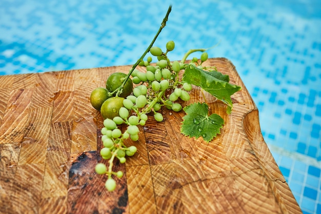 Fresh green unripe grapes, tangerines and mangoes on a wooden background in blue water