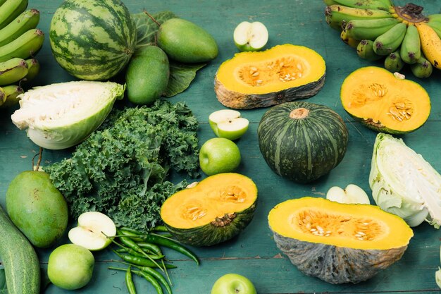 Fresh green vegetables and fruits on green wooden background