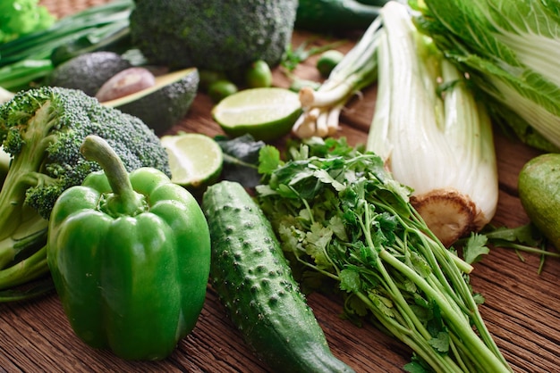 木製の背景に新鮮な緑の野菜や果物や緑。健康的な食事のコンセプト