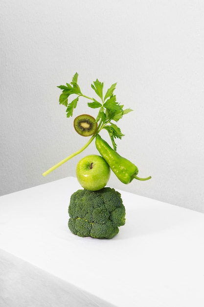 Fresh green vegetables and fruits on white table. Equilibrium floating food