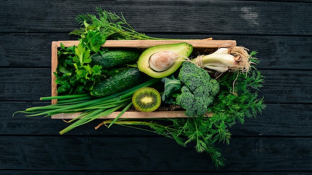 Fresh green vegetables and fruits in a wooden basket healthy food top view copy space