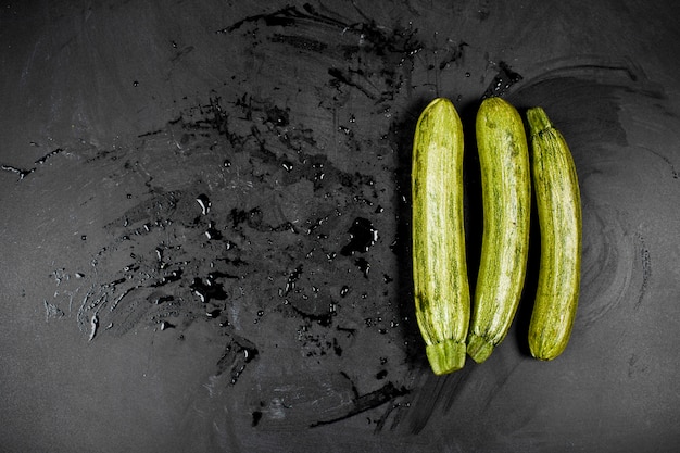 Fresh green wet zucchini on blackboard background. 