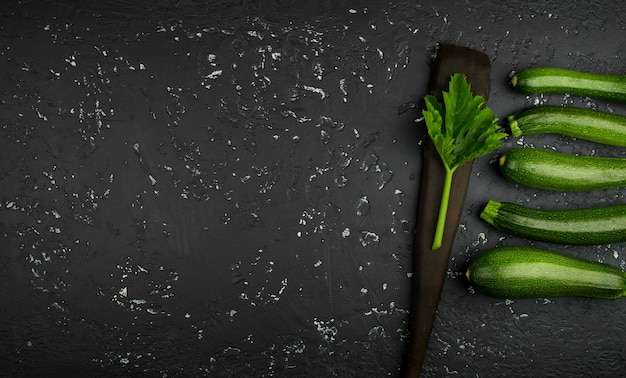 Fresh green zucchini on a dark table  in top view with copy space