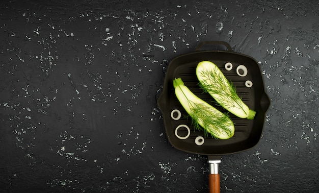 Fresh green zucchini in a pan on a dark table. The view from the top. Copy space.