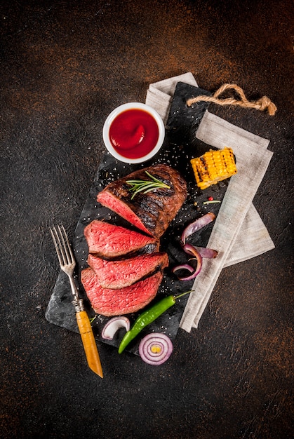 Fresh grilled beef, homemade bbq meat medium rare, on black stone cutting board, with spices