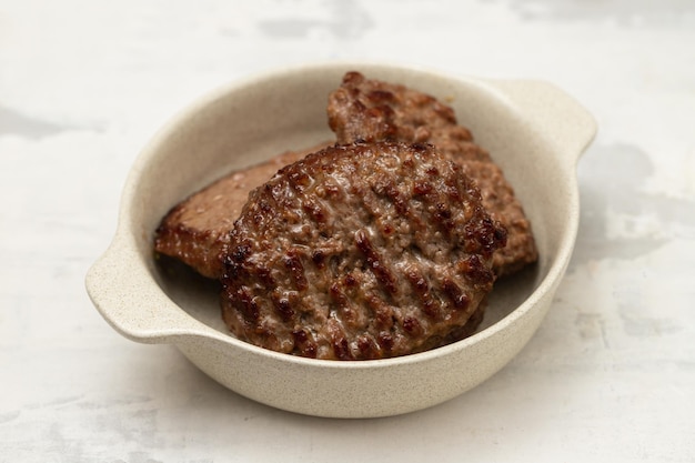 Fresh grilled hamburgers in small bowl on ceramic