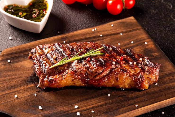 Photo fresh grilled meat. grilled beef steak medium rare on wooden board. top view.