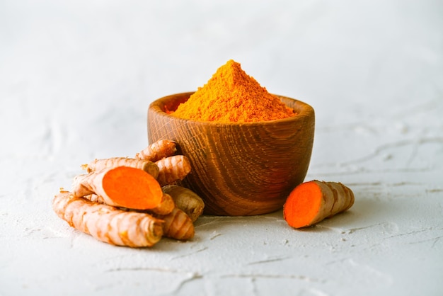 fresh and ground turmeric in a wooden bowl