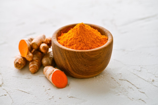 fresh and ground turmeric in a wooden bowl