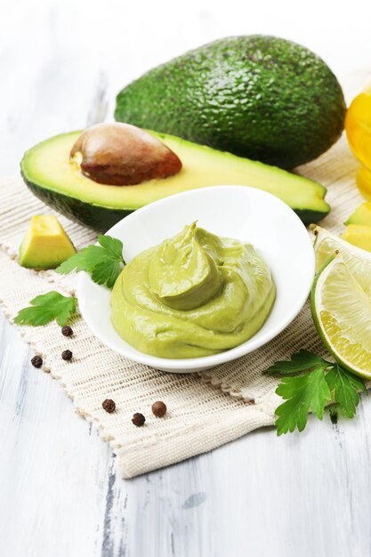 Fresh guacamole in bowl on wooden table