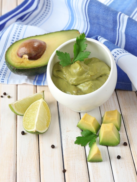 Fresh guacamole in bowl on wooden table