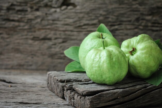 Fresh guava with green leaves on wooden background.